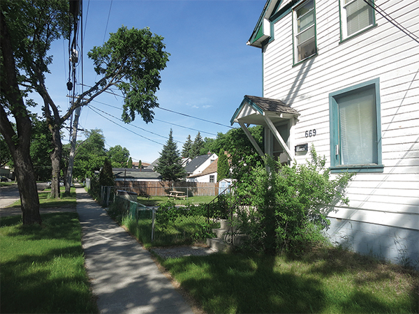 Front and back yards. In a curiousity featured in the 2007 film My Winnipeg, the house at right faces south onto Scotland Avenue while its neighbours face north onto Lorette Avenue.