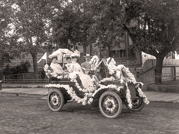 Bain was at the wheel of one of his automobiles (decorated for a parade) in front of the family residence on Fort Street, July 1905, along with his sister Elizabeth (rear seat, left) and beloved cousin Ella (front seat passenger).