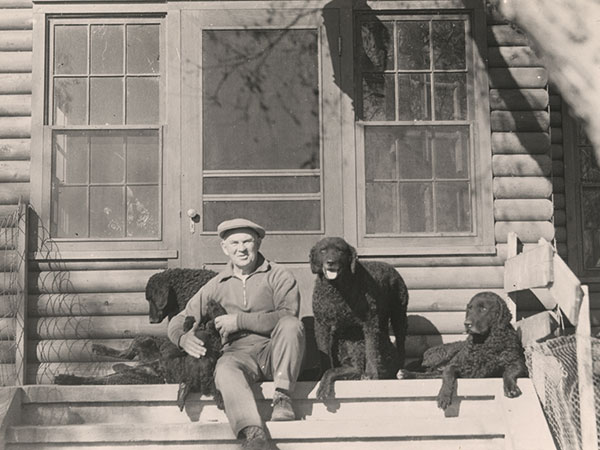 Bain with his curlies. This view of Dan Bain relaxing on the steps of Mallard Lodge shows him with five of his beloved curly-coated retrievers. He rarely went anywhere without at least one of them.