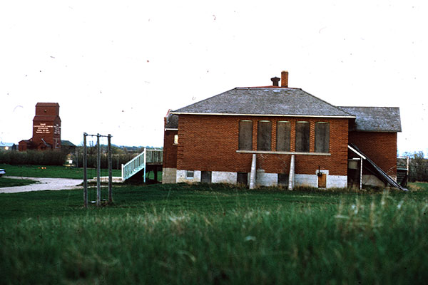 The former Dand School building with the Manitoba Pool grain elevator in the background