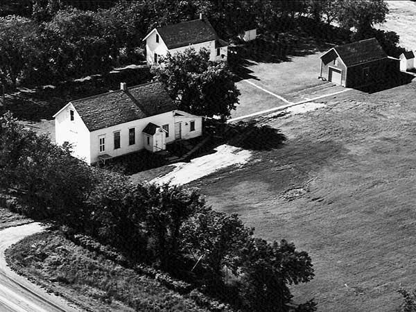 Aerial view of the Edenburg School site, showing a larger teacherage moved to the site following the 1953 amalgamation with Edenthal School. Also visible is the barn used to house horses ridden to school by students, and a pair of outhouses for boys and girls. 