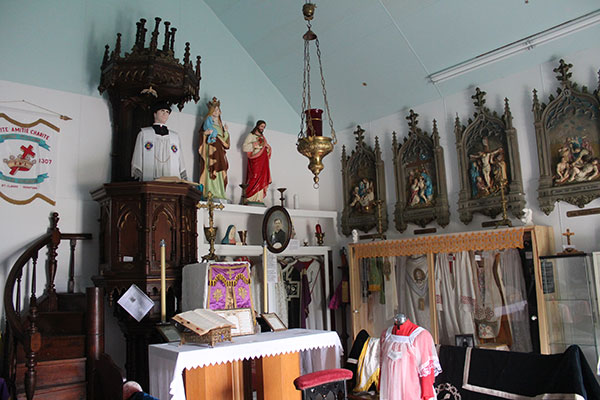 Interior of a chapel containing religious artifacts from St. Claude's two previous churches
