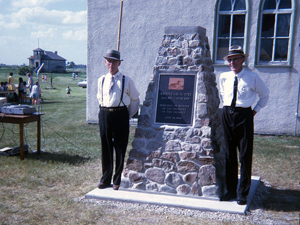 Regent School commemorative monument unveiling with school district secretary-treasurer Bert Hatton at left and trustee and chairman W. L. “Bill” Fox at right and the former school building in the left background and the Regent United Church immediate behind the monument