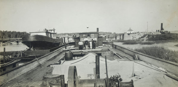 The deck of the Marvyl, with J. R. Spear (left, loaded aboard a barge) south of the Fairford Railway Bridge and St. Helen’s Anglican Church in the background