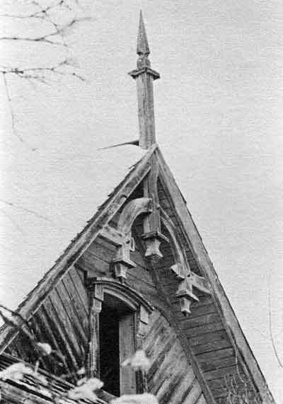 Finial and pendant decorate the gable end in a Swiss Chalet detailing. Wooden labels appear above windows on a second and third storeys.