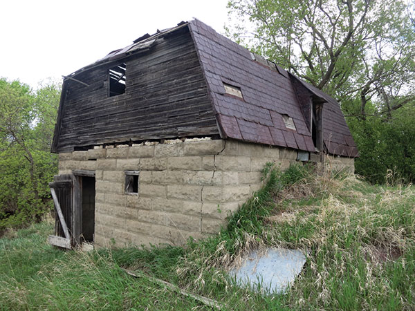 Booth Concrete Granary (RM of North Norfolk). This unique building, near the village of Sidney, was constructed by Frank Thomson for the Booth family. It is situated on the side of a hill so the farmer could transfer the harvested crops into the granary from the uphill side and, when it was time to deliver grain to a local elevator, it was a simple matter of parking a wagon on the downhill side and letting gravity do the work. The downhill side of the building had two openings, one for the main floor and one for an upper floor, so the farmer could store grain on both levels.