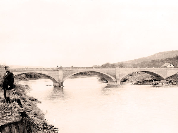 An impressive triple-arch concrete bridge over the Assiniboine River, in the village of Millwood in the Rural Municipality of Russell, was built in 1920, replacing an earlier wooden structure. Aside from minor damage to the balusters of its railings, it is in good condition.