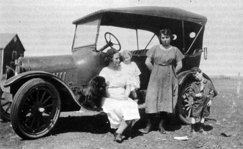 Women and children with early Chevrolet automobile near Morden