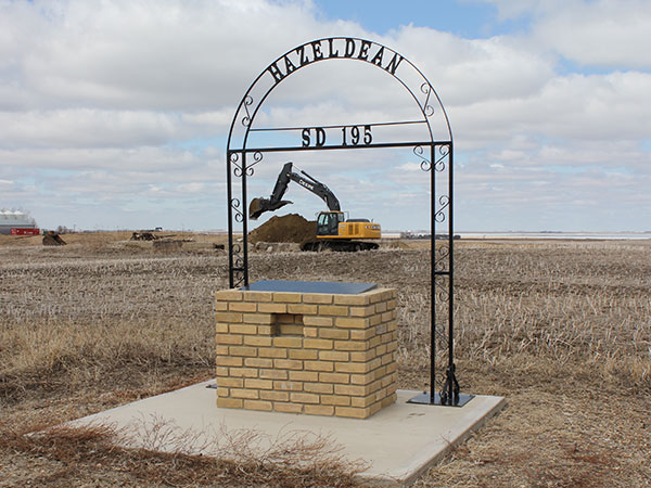 Hazeldean School commemorative monument with the concrete foundation of the former schoolhouse in the background