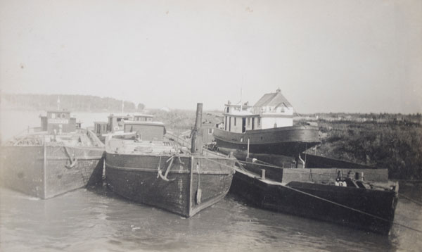 Marvyl (left) on Dauphin River with Alexander (centre) and J. R. Spear (loaded atop another barge), north of the Fairford Railway Bridge, with St. Helen’s Anglican Church in the background